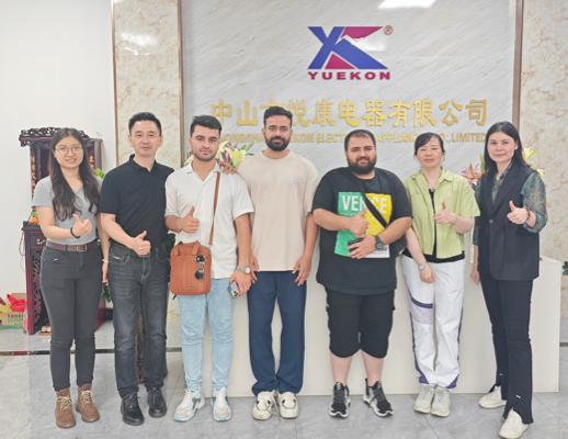 Zhongshan Yuekon Electrical Appliances Co., Limited 직원과 국제 고객이 함께 포즈를 취하며 성공적이고 협력적인 비즈니스 관계를 상징합니다.